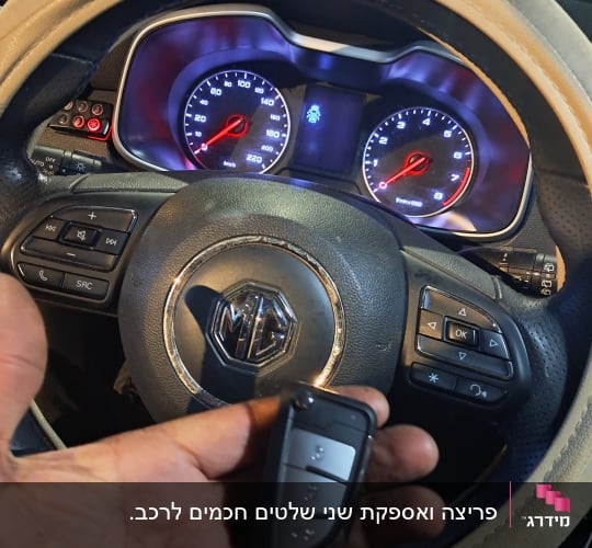 מפתח רכב חכם ביד מול הגה ומד מהירות